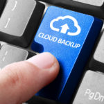 Back up online via cloud. gesture of finger pressing cloud backup button on a computer keyboard